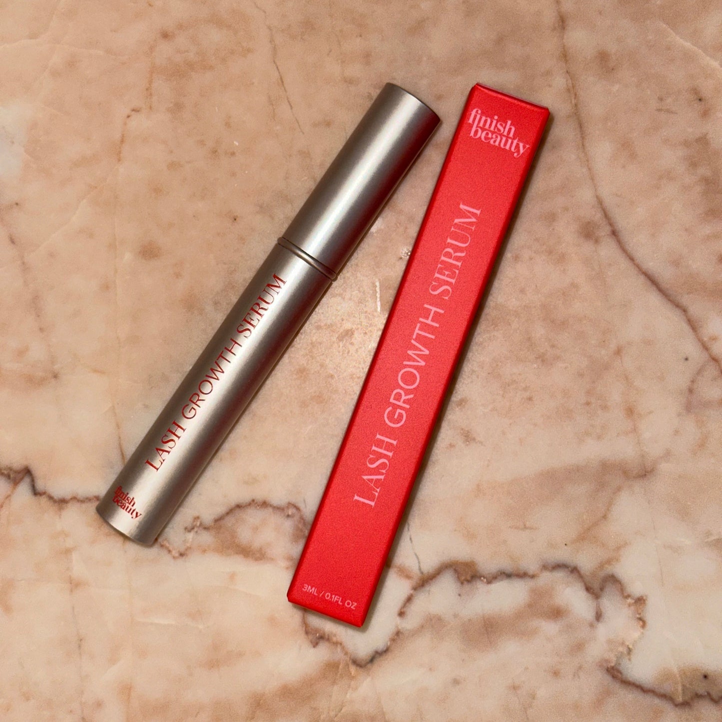 Eyelash growth serum with red packaging on a marble surface